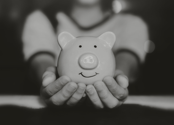 Woman holding a smiling piggybank in her hands towards the viewer